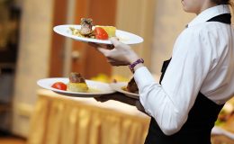 Waitress carrying three plates with meat dish